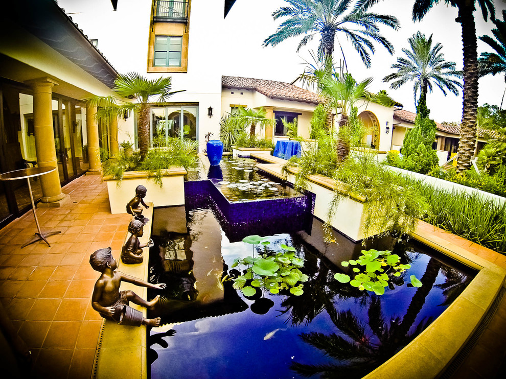 Inspiration for a large mediterranean courtyard patio in Tampa with a water feature, brick pavers and no cover.