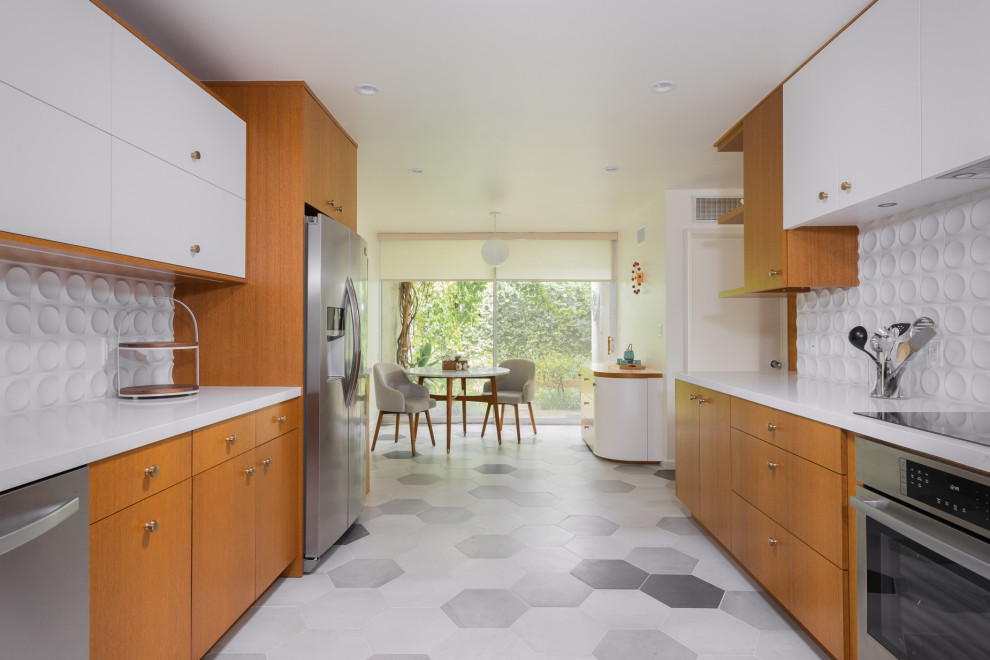 This is an example of a mid-sized midcentury u-shaped eat-in kitchen in Los Angeles with an undermount sink, flat-panel cabinets, medium wood cabinets, quartz benchtops, white splashback, ceramic splashback, stainless steel appliances, porcelain floors, grey floor and white benchtop.