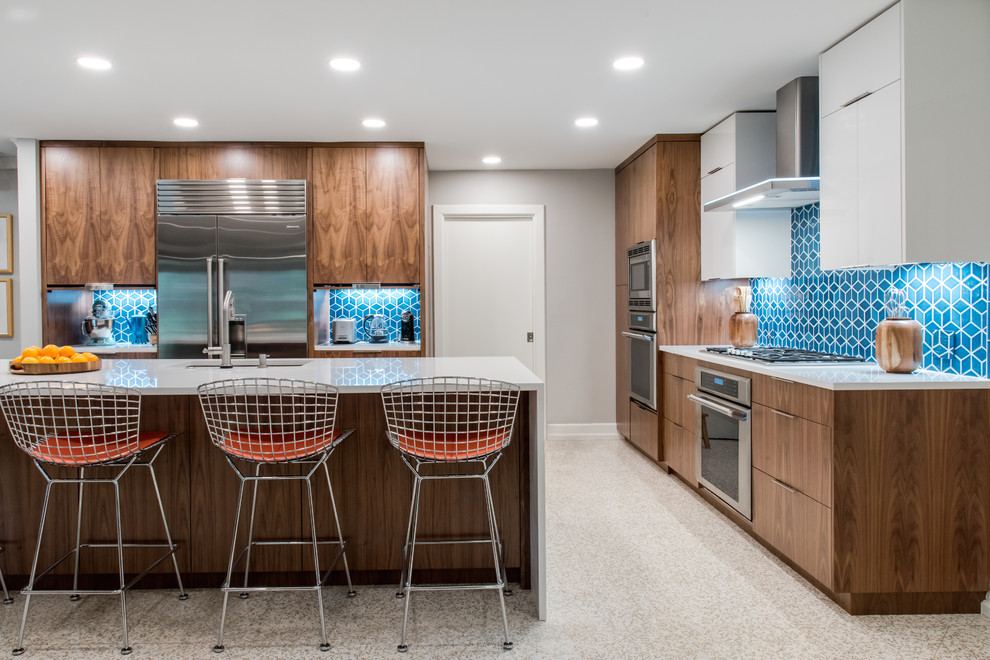 Mid-sized contemporary l-shaped eat-in kitchen in Austin with medium wood cabinets, blue splashback, ceramic splashback, stainless steel appliances, with island, beige floor, an undermount sink, flat-panel cabinets and white benchtop.