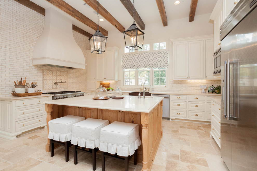 Design ideas for a traditional u-shaped kitchen in New Orleans with a farmhouse sink, raised-panel cabinets, white cabinets, white splashback, subway tile splashback and stainless steel appliances.