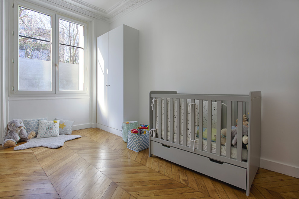 Design ideas for a large traditional nursery for boys in Other with white walls and light hardwood floors.