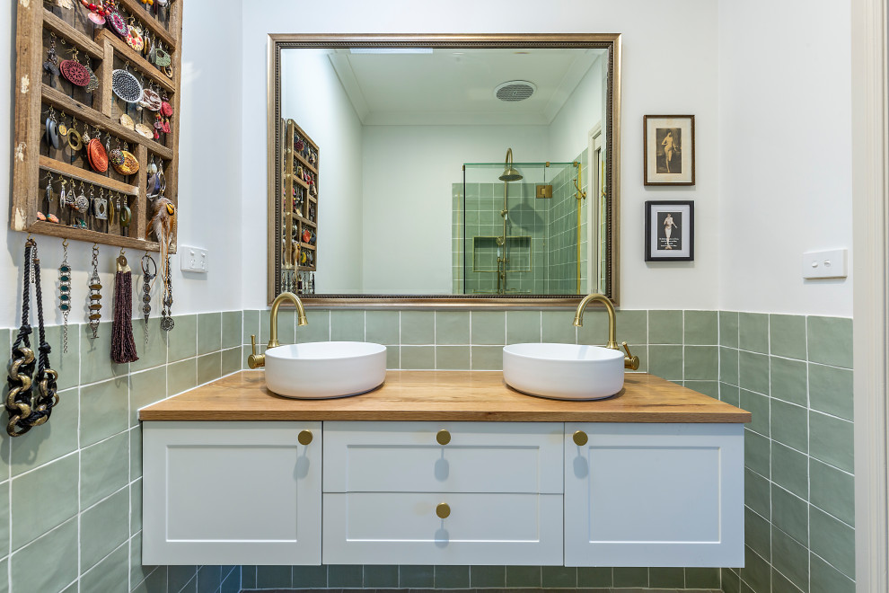 Пример оригинального дизайна: маленькая ванная комната в викторианском стиле с фасадами в стиле шейкер, белыми фасадами, отдельно стоящей ванной, зеленой плиткой, плиткой кабанчик, белыми стенами, полом из керамогранита, столешницей из дерева, бежевым полом, душем с распашными дверями, коричневой столешницей, нишей, тумбой под две раковины и подвесной тумбой для на участке и в саду
