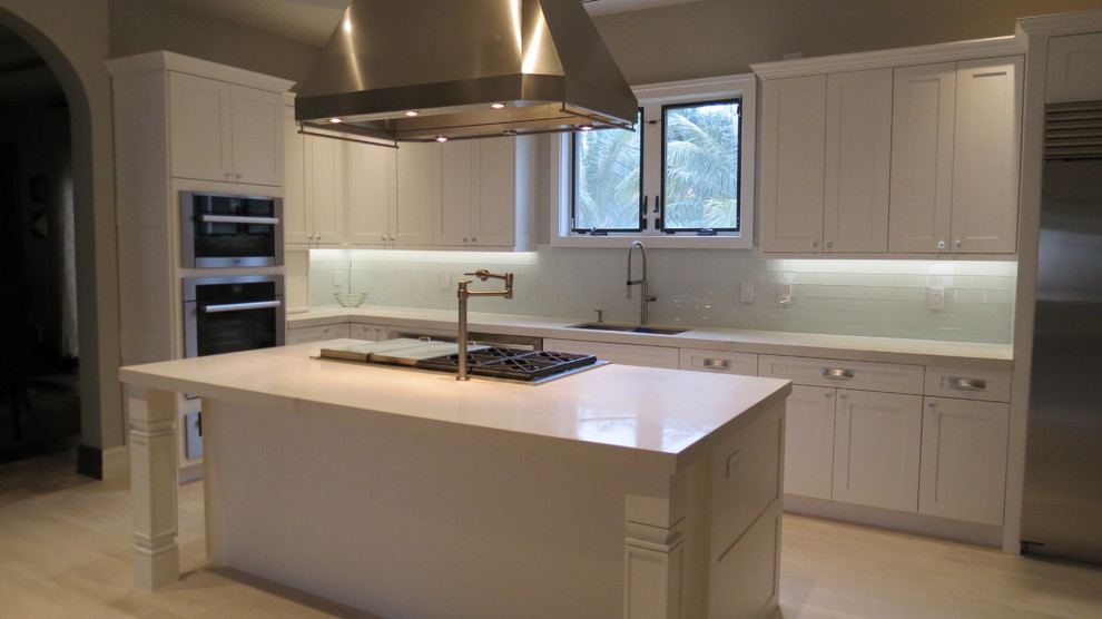 Enclosed kitchen - large transitional l-shaped light wood floor and beige floor enclosed kitchen idea with a double-bowl sink, shaker cabinets, white cabinets, marble countertops, blue backsplash, glass tile backsplash, stainless steel appliances and an island