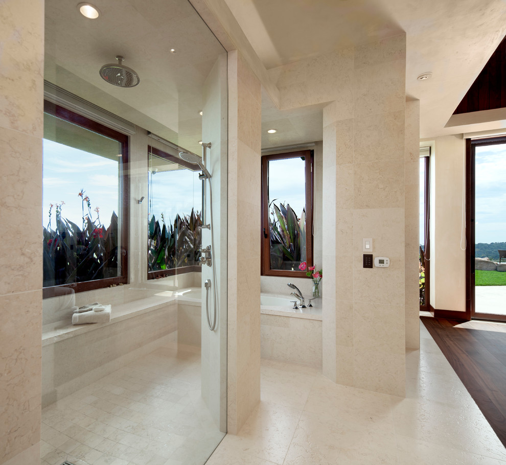 Inspiration for a large tropical master bathroom in Santa Barbara with an alcove tub, a curbless shower, beige tile, stone tile, beige walls and limestone floors.