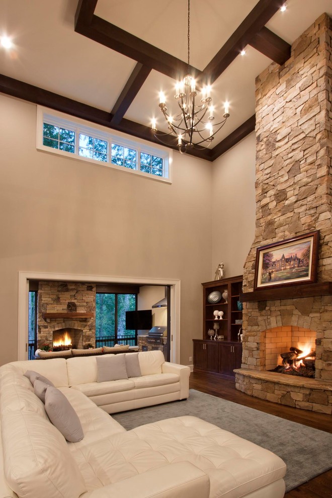 Photo of a large transitional formal open concept living room in Other with a stone fireplace surround, beige walls, medium hardwood floors, a standard fireplace, a built-in media wall and brown floor.