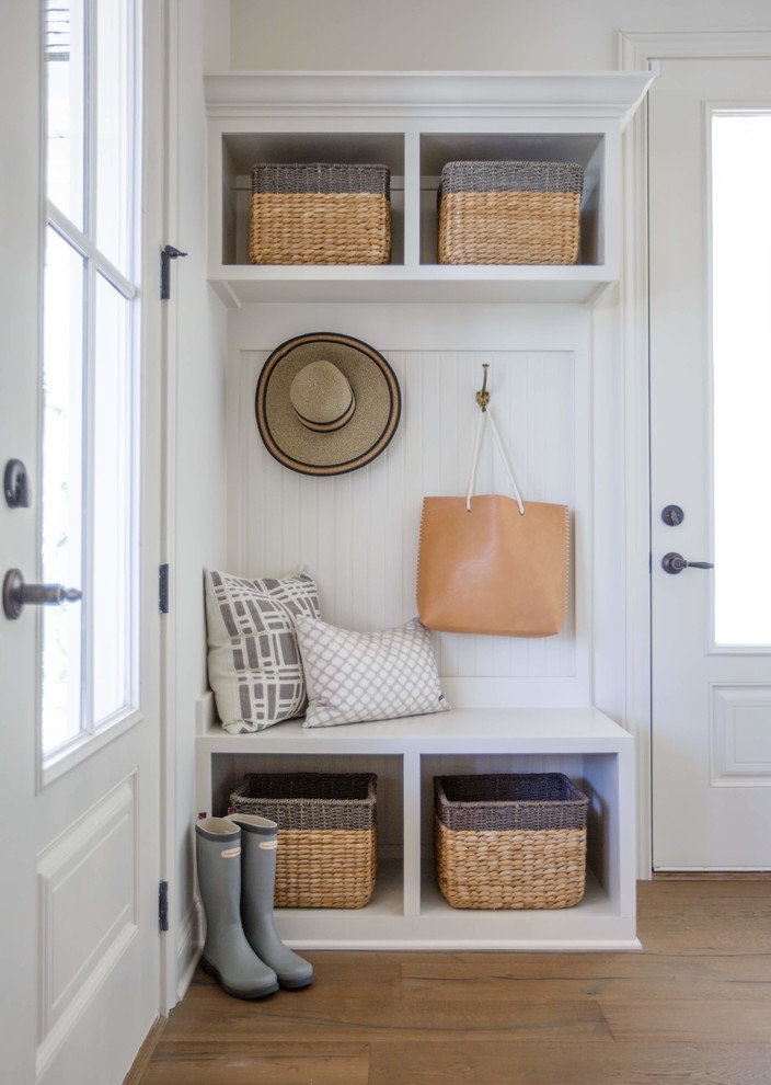 Beach style mudroom in Jacksonville with white walls, medium hardwood floors and a glass front door.