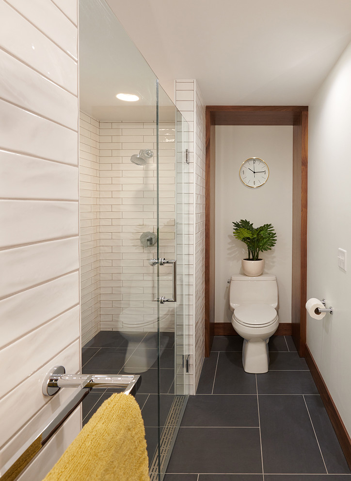 Inspiration for a mid-sized midcentury master bathroom in Minneapolis with flat-panel cabinets, medium wood cabinets, a curbless shower, a two-piece toilet, white tile, ceramic tile, white walls, ceramic floors, an undermount sink, engineered quartz benchtops, grey floor, a hinged shower door and white benchtops.