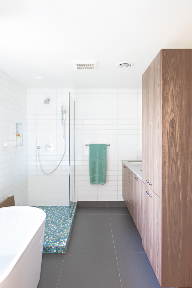 Inspiration for a mid-sized midcentury master bathroom in Seattle with flat-panel cabinets, dark wood cabinets, a freestanding tub, a corner shower, white tile, white walls, ceramic floors, grey floor and an open shower.