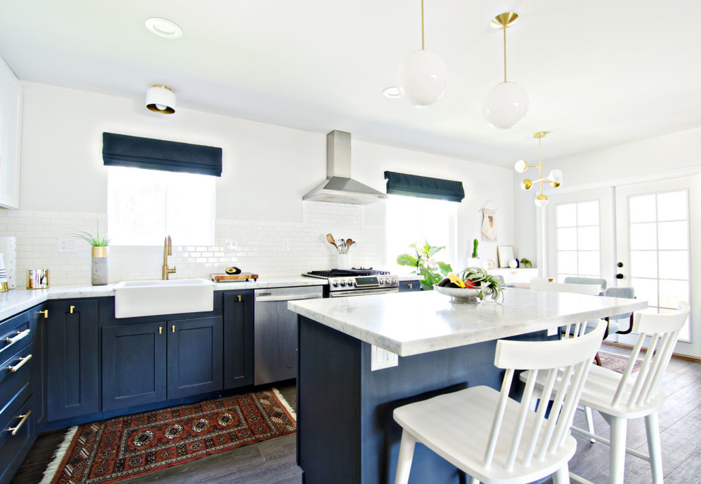 Design ideas for a mid-sized midcentury l-shaped eat-in kitchen in San Francisco with a farmhouse sink, shaker cabinets, blue cabinets, marble benchtops, white splashback, ceramic splashback, stainless steel appliances, dark hardwood floors and with island.