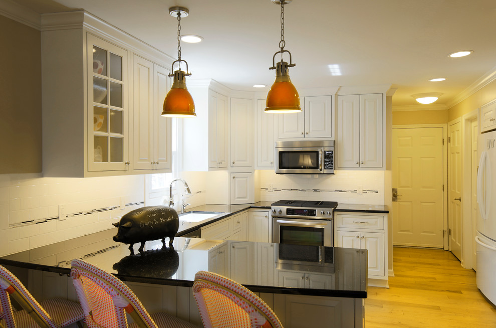 Transitional u-shaped medium tone wood floor kitchen photo in Chicago with an undermount sink, raised-panel cabinets, white cabinets, granite countertops, white backsplash, subway tile backsplash and stainless steel appliances
