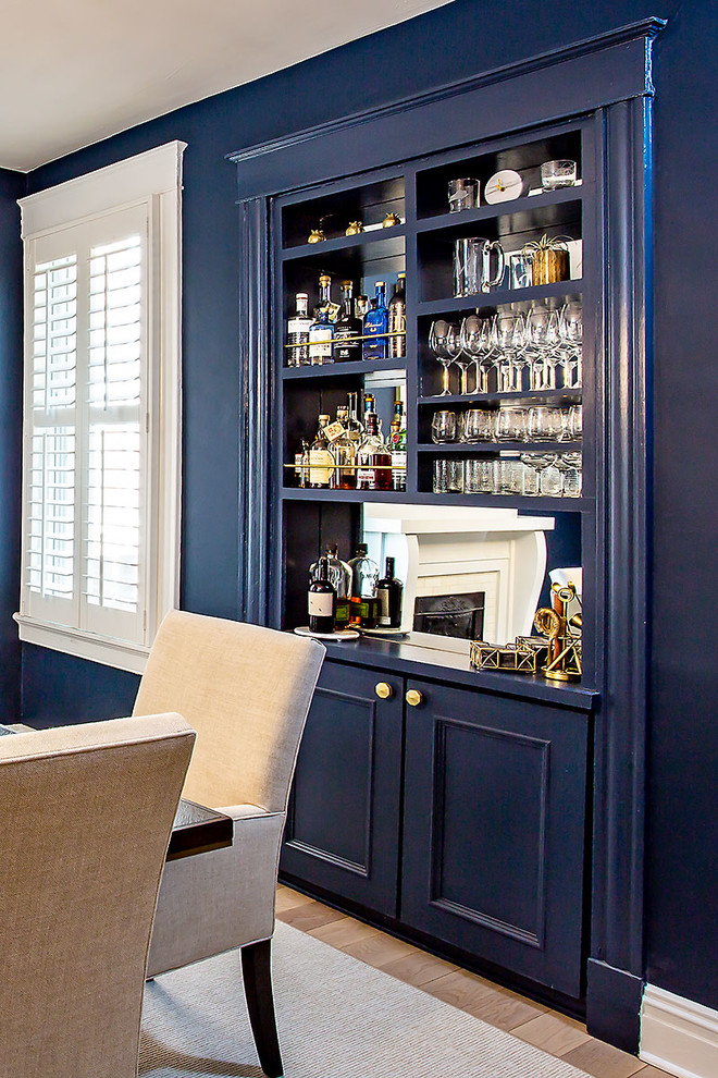 This is an example of a small traditional single-wall home bar in Richmond with light hardwood floors, no sink, open cabinets, blue cabinets, mirror splashback, beige floor and blue benchtop.