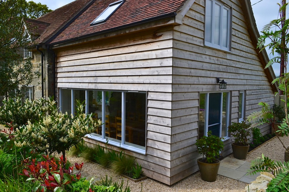 This is an example of a country two-storey exterior in Dorset with wood siding and a gable roof.