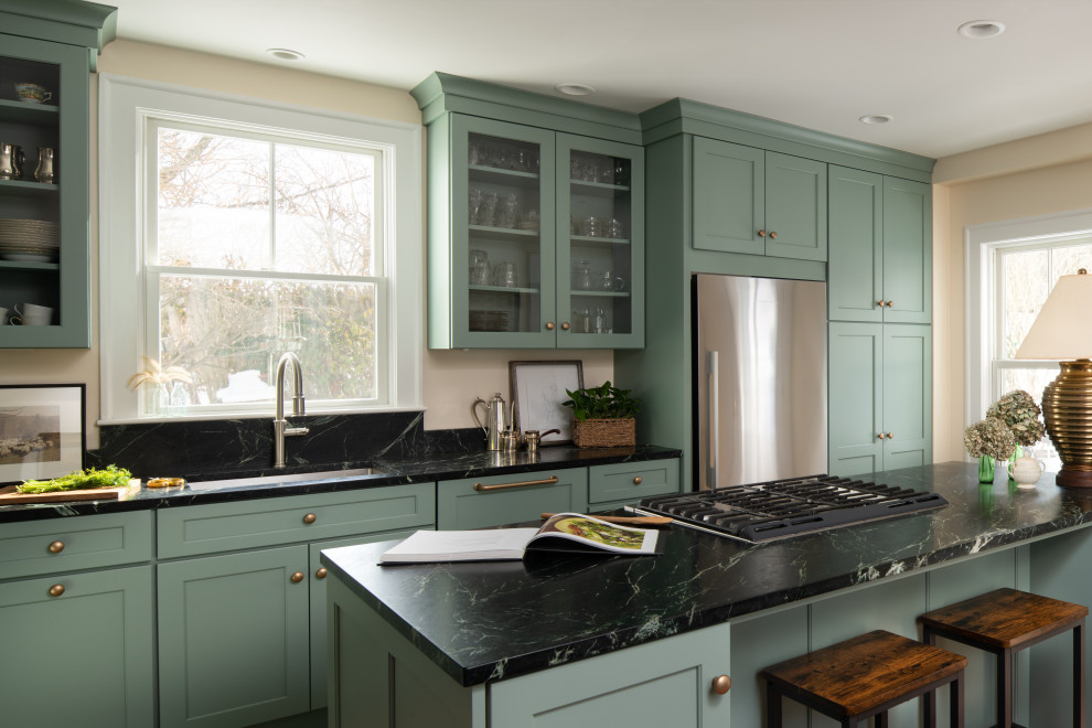 Design ideas for a traditional kitchen in Boston with an undermount sink, glass-front cabinets, green cabinets, black splashback, stainless steel appliances, with island and black benchtop.