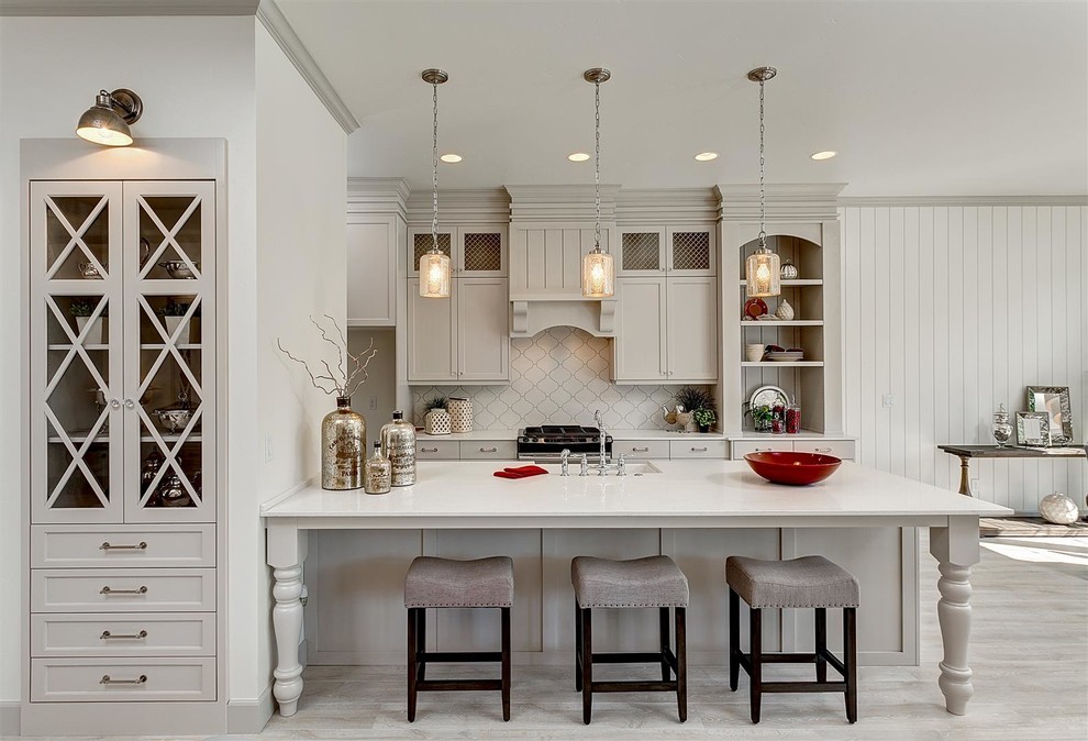 Inspiration for a mid-sized traditional galley open plan kitchen in Boise with an undermount sink, shaker cabinets, grey cabinets, white splashback, light hardwood floors, a peninsula, quartz benchtops and stainless steel appliances.