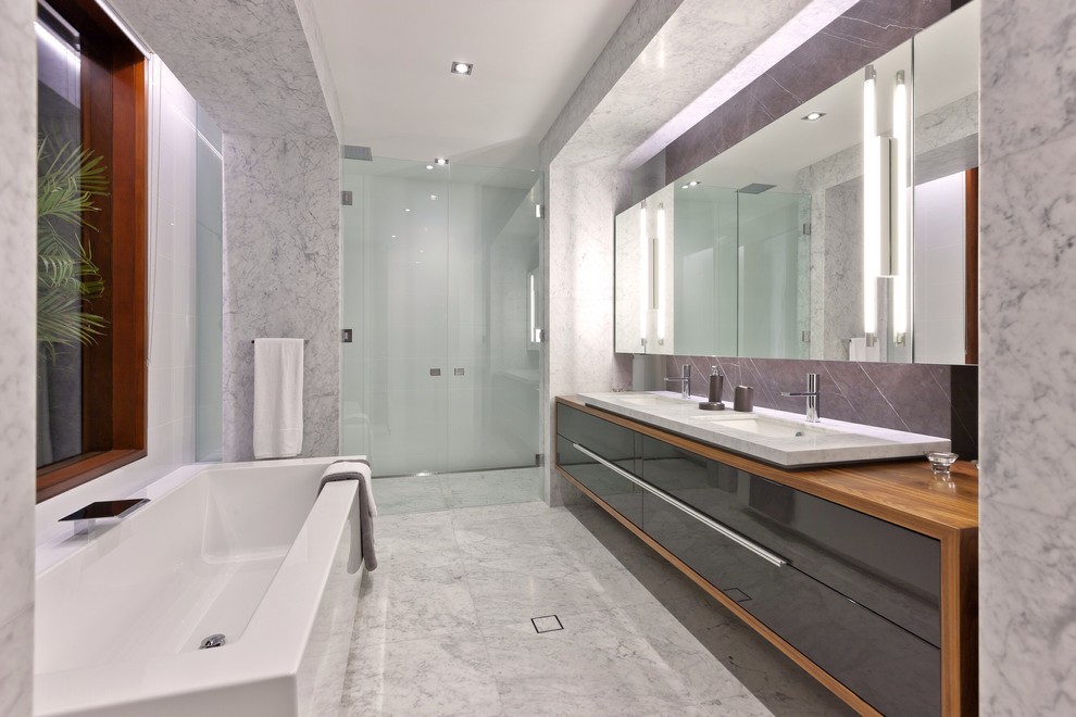 Photo of a mid-sized contemporary master bathroom in Perth with a vessel sink, recessed-panel cabinets, grey cabinets, wood benchtops, a freestanding tub, an alcove shower, white tile, subway tile, white walls and marble floors.