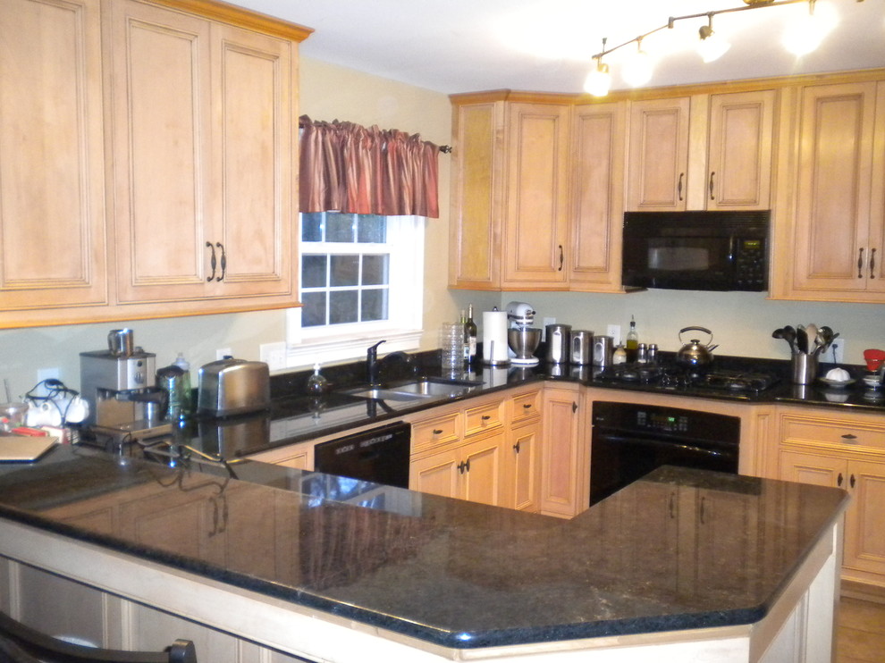 This is an example of a traditional eat-in kitchen in Other with a double-bowl sink, raised-panel cabinets, light wood cabinets, granite benchtops and black appliances.