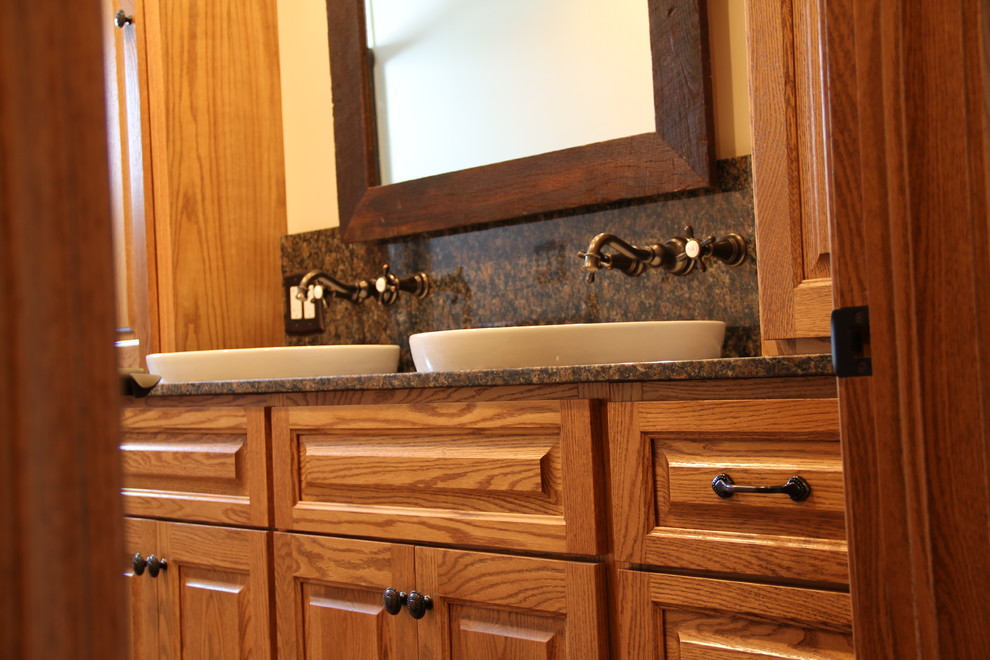 Transitional brown tile and porcelain tile porcelain tile tub/shower combo photo in Columbus with a vessel sink, an undermount tub, a two-piece toilet, raised-panel cabinets, medium tone wood cabinets, granite countertops and beige walls