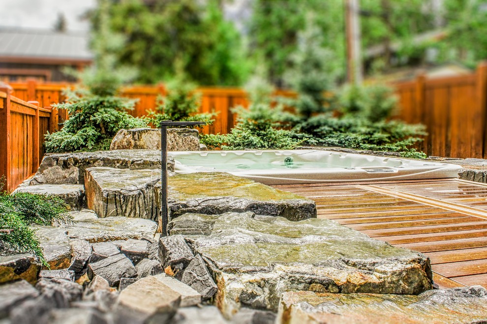 Photo of a mid-sized traditional backyard custom-shaped pool in Calgary with a hot tub and natural stone pavers.