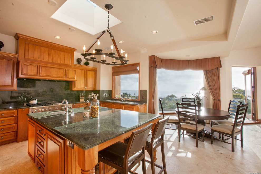 This is an example of a traditional eat-in kitchen in San Diego with raised-panel cabinets, medium wood cabinets, green splashback, stone slab splashback, stainless steel appliances and green benchtop.