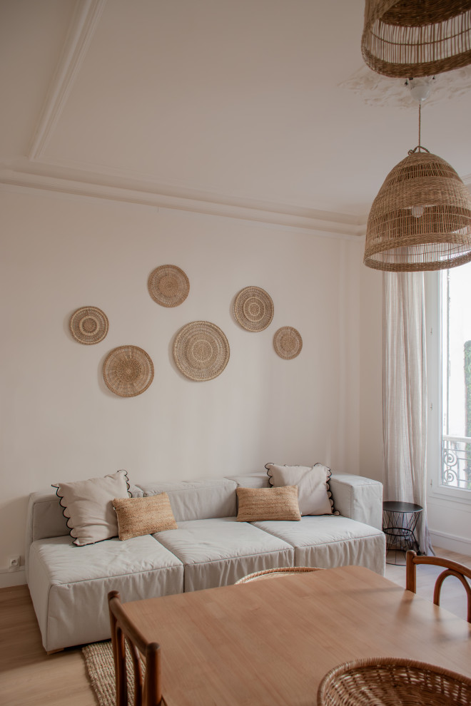 Стильный дизайн: гостиная комната в белых тонах с отделкой деревом в средиземноморском стиле с белыми стенами, полом из ламината, стандартным камином и фасадом камина из камня - последний тренд