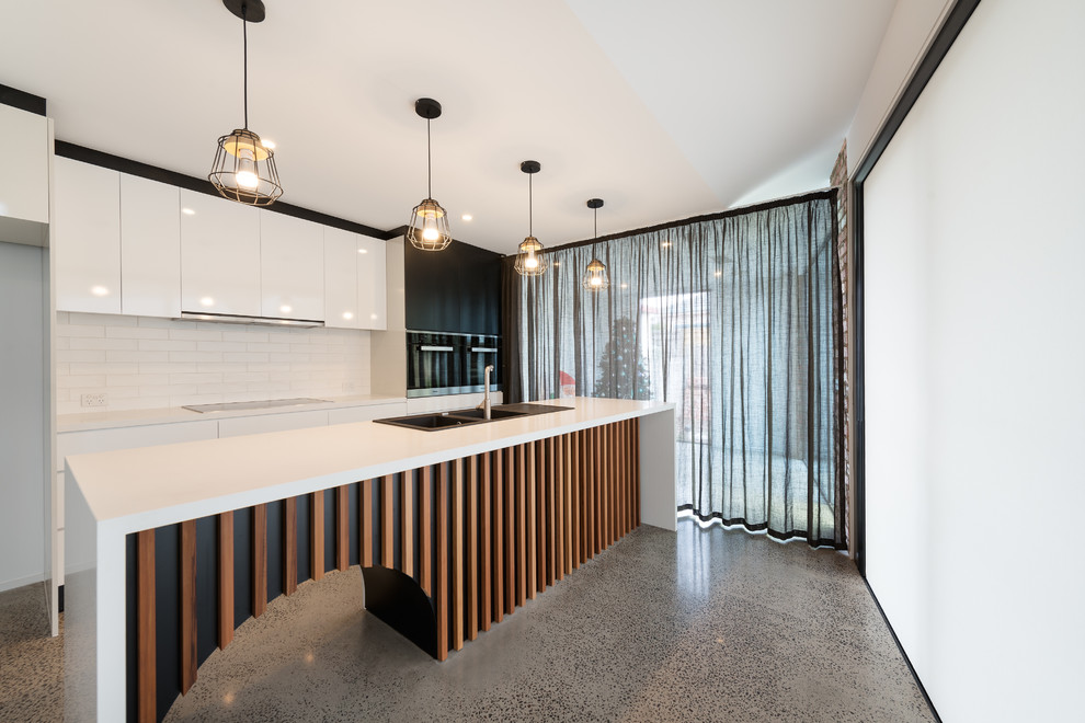 Photo of a mid-sized contemporary galley eat-in kitchen in Melbourne with white splashback, ceramic splashback, travertine floors, with island, a double-bowl sink, flat-panel cabinets and white cabinets.