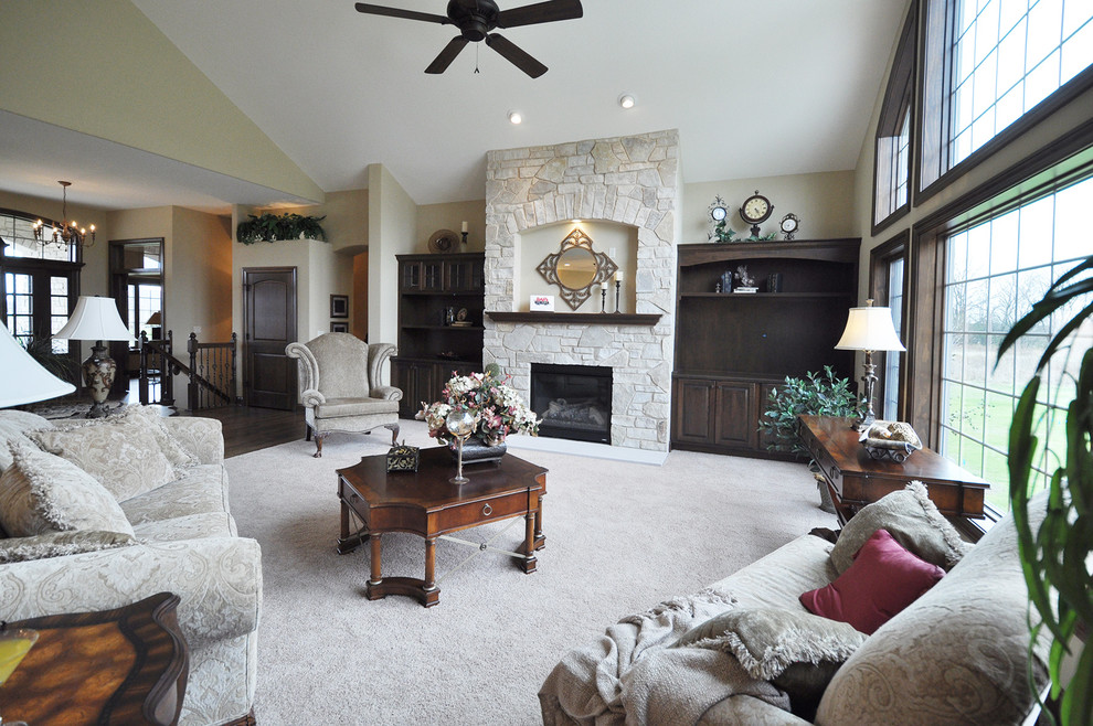 This is an example of a large traditional open concept living room in Milwaukee with beige walls, carpet, a standard fireplace, a stone fireplace surround and a built-in media wall.
