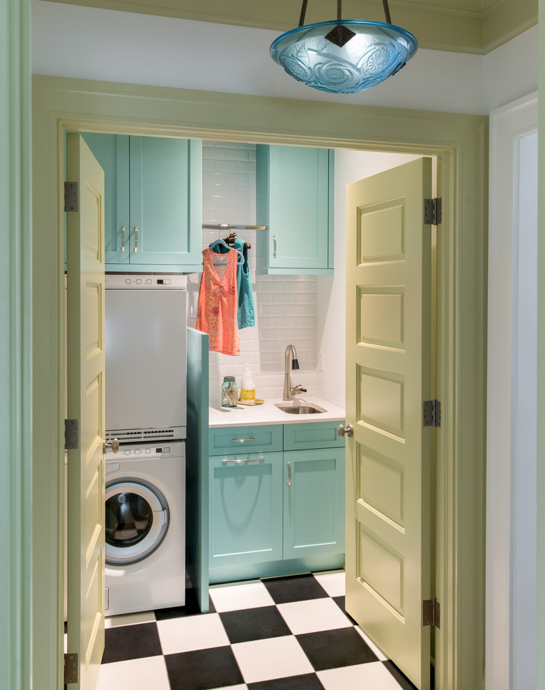 Traditional single-wall dedicated laundry room in Denver with an undermount sink, shaker cabinets, blue cabinets, white walls, a stacked washer and dryer and multi-coloured floor.