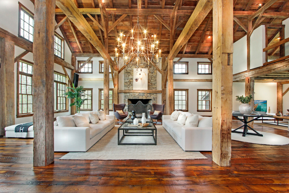 Design ideas for an expansive rustic open plan living room in New York with white walls, medium hardwood flooring, a standard fireplace, a stacked stone fireplace surround, a wall mounted tv and a vaulted ceiling.