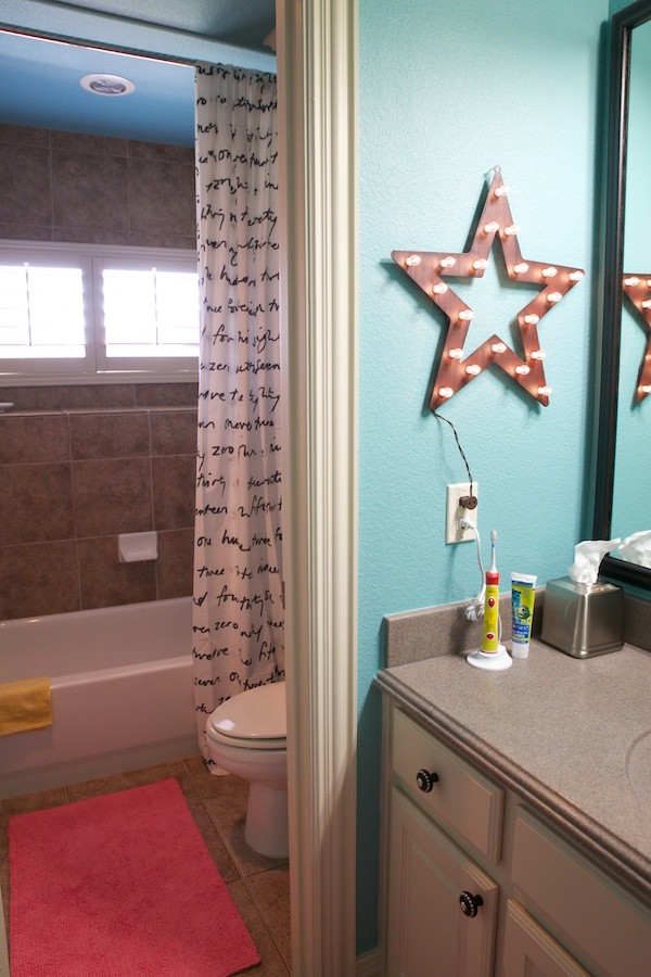 Inspiration for a small eclectic kids bathroom in Dallas with an integrated sink, raised-panel cabinets, beige cabinets, solid surface benchtops, an alcove tub, a shower/bathtub combo, a two-piece toilet, brown tile, ceramic tile, blue walls and ceramic floors.