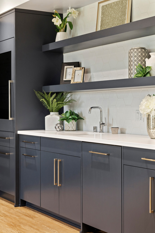 Design ideas for an expansive contemporary l-shaped wet bar in Minneapolis with an undermount sink, flat-panel cabinets, blue cabinets, quartz benchtops, white splashback, ceramic splashback, medium hardwood floors and white benchtop.