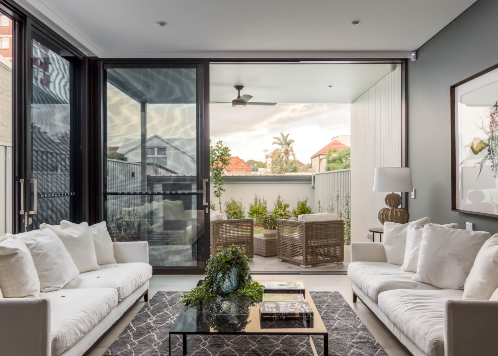 This is an example of a large contemporary formal open concept living room in Sydney with white walls, ceramic floors, no fireplace, a freestanding tv and beige floor.