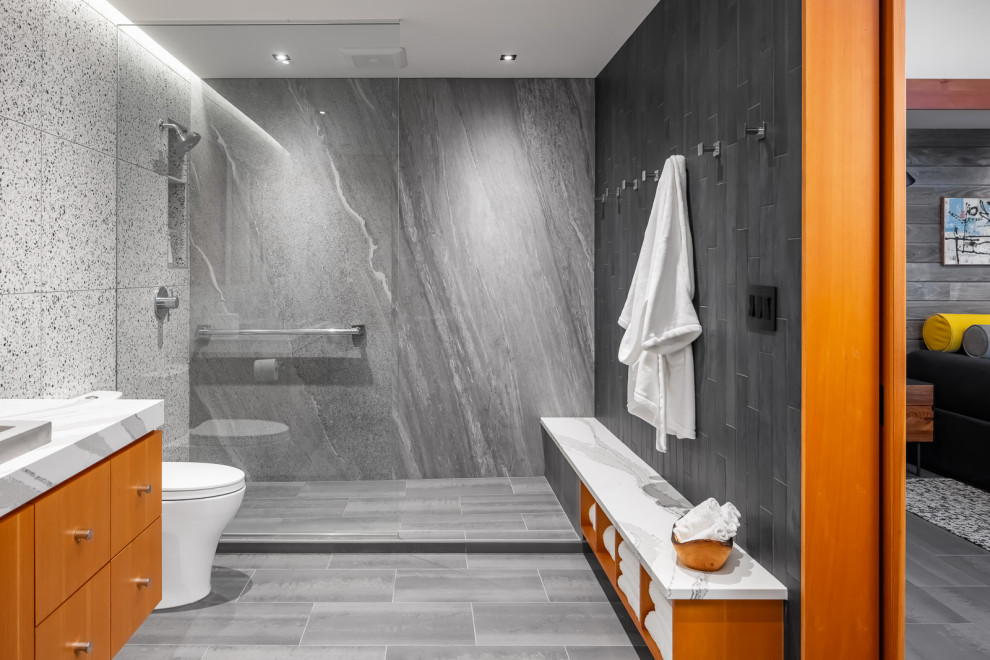 Photo of a mid-sized country master bathroom in Minneapolis with flat-panel cabinets, medium wood cabinets, a freestanding tub, an open shower, a two-piece toilet, black and white tile, porcelain tile, grey walls, porcelain floors, a trough sink, engineered quartz benchtops, grey floor, white benchtops, a shower seat, a single vanity and a floating vanity.