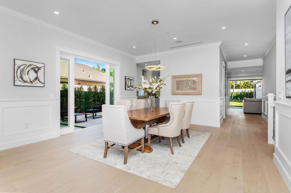 Large traditional dining room in Los Angeles with light hardwood flooring, beige floors and wainscoting.