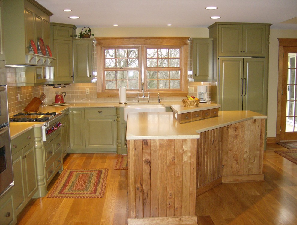 Inspiration for a large country l-shaped eat-in kitchen in Milwaukee with a farmhouse sink, green cabinets, beige splashback, medium hardwood floors, with island, raised-panel cabinets and panelled appliances.