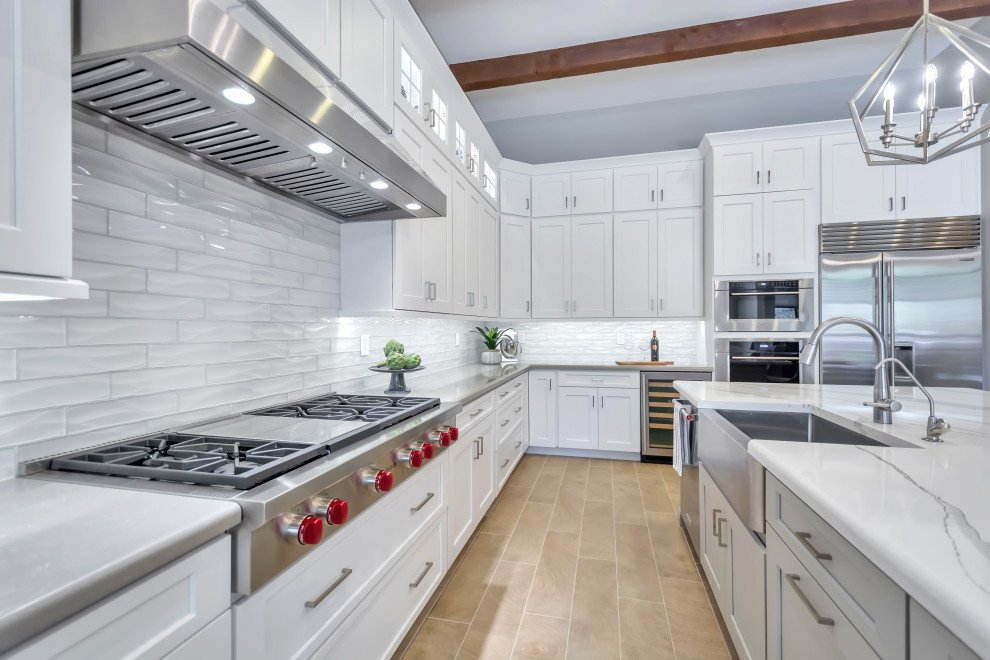 Large transitional l-shaped porcelain tile and brown floor eat-in kitchen photo in Phoenix with a farmhouse sink, shaker cabinets, white cabinets, quartz countertops, white backsplash, subway tile backsplash, stainless steel appliances, an island and gray countertops