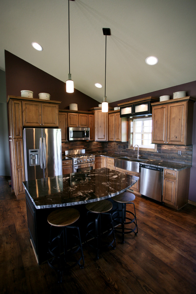 Mid-sized mountain style l-shaped dark wood floor and brown floor open concept kitchen photo in Minneapolis with a farmhouse sink, raised-panel cabinets, medium tone wood cabinets, granite countertops, brown backsplash, wood backsplash, stainless steel appliances and an island