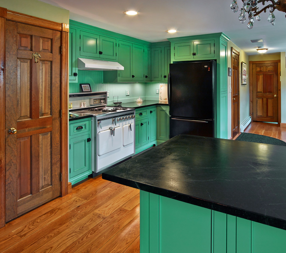 Design ideas for a mid-sized eclectic l-shaped eat-in kitchen in Providence with a drop-in sink, beaded inset cabinets, green cabinets, soapstone benchtops, green splashback, timber splashback, black appliances, medium hardwood floors and no island.