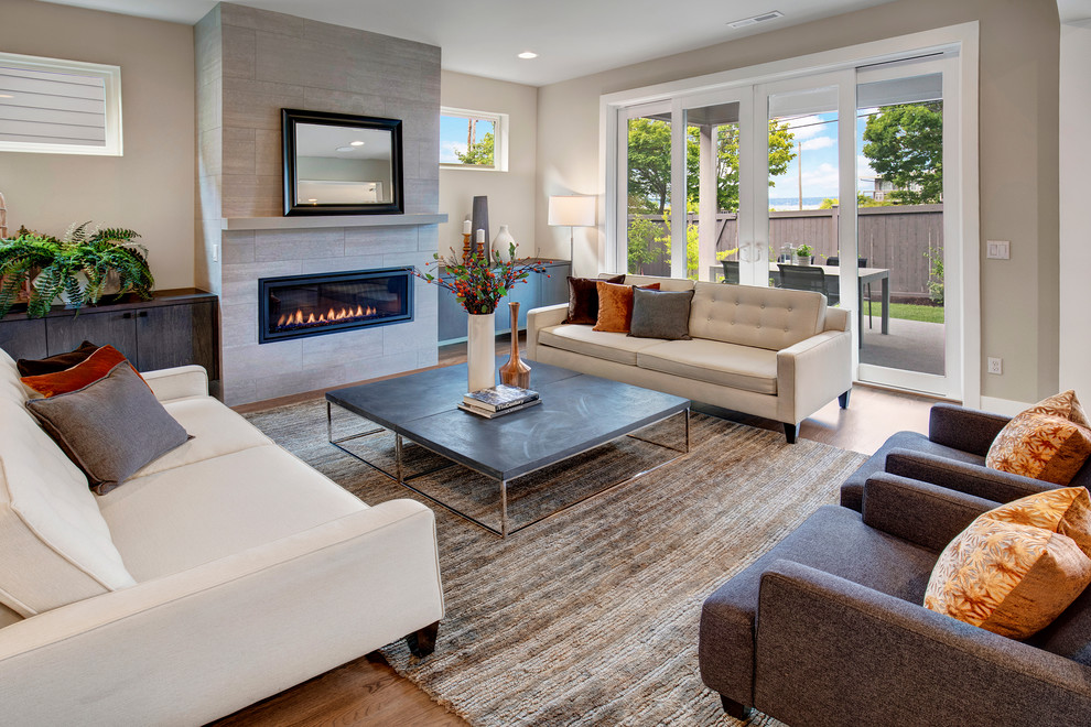 Contemporary open concept living room in Seattle with medium hardwood floors, a standard fireplace, a tile fireplace surround and a wall-mounted tv.