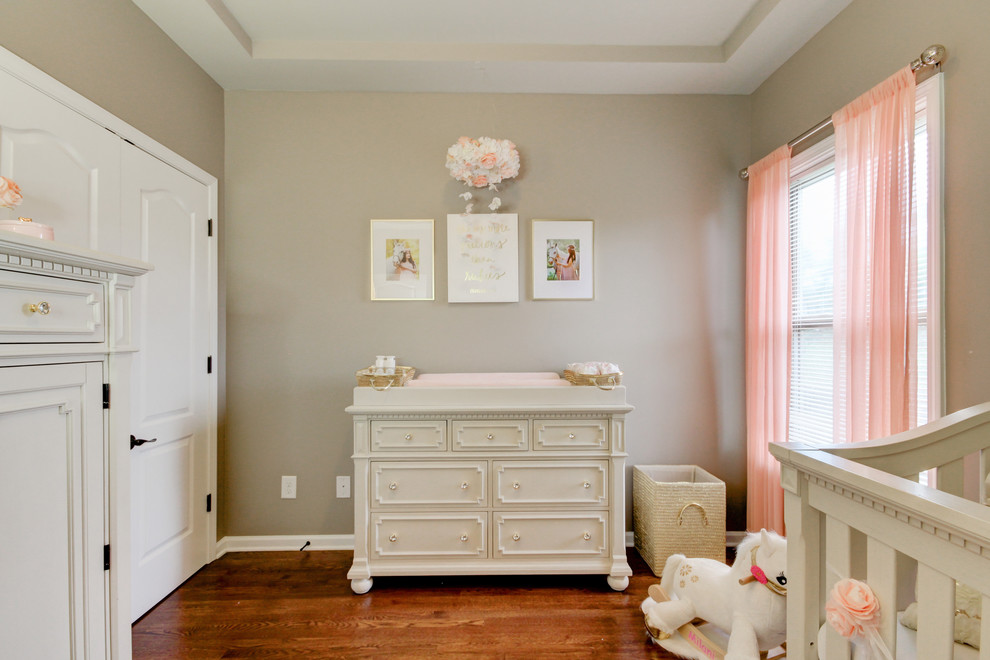 Design ideas for a small traditional nursery for girls in Nashville with grey walls, medium hardwood floors and brown floor.