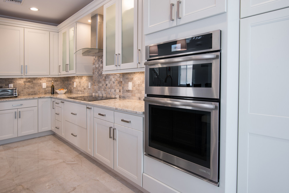Example of a large transitional l-shaped open concept kitchen design in Miami with an undermount sink, shaker cabinets, white cabinets, granite countertops, beige backsplash, stone tile backsplash, stainless steel appliances and an island