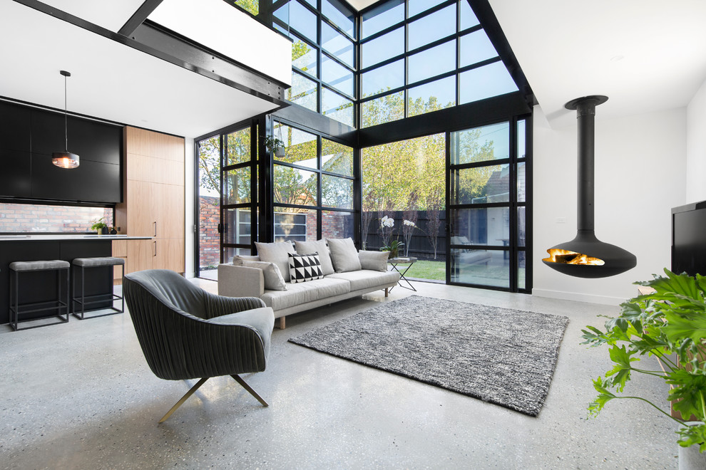 This is an example of a contemporary open concept living room in Melbourne with white walls and a hanging fireplace.