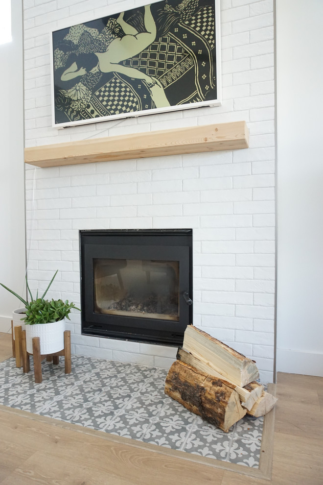 Inspiration for a small country living room in Other with white walls, light hardwood floors, a wood stove, a brick fireplace surround, a wall-mounted tv and yellow floor.