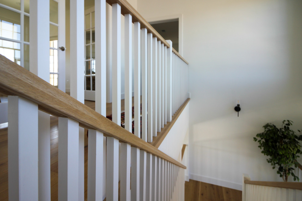 Imagen de escalera en U de estilo de casa de campo de tamaño medio con escalones de madera, contrahuellas de madera, barandilla de madera y machihembrado