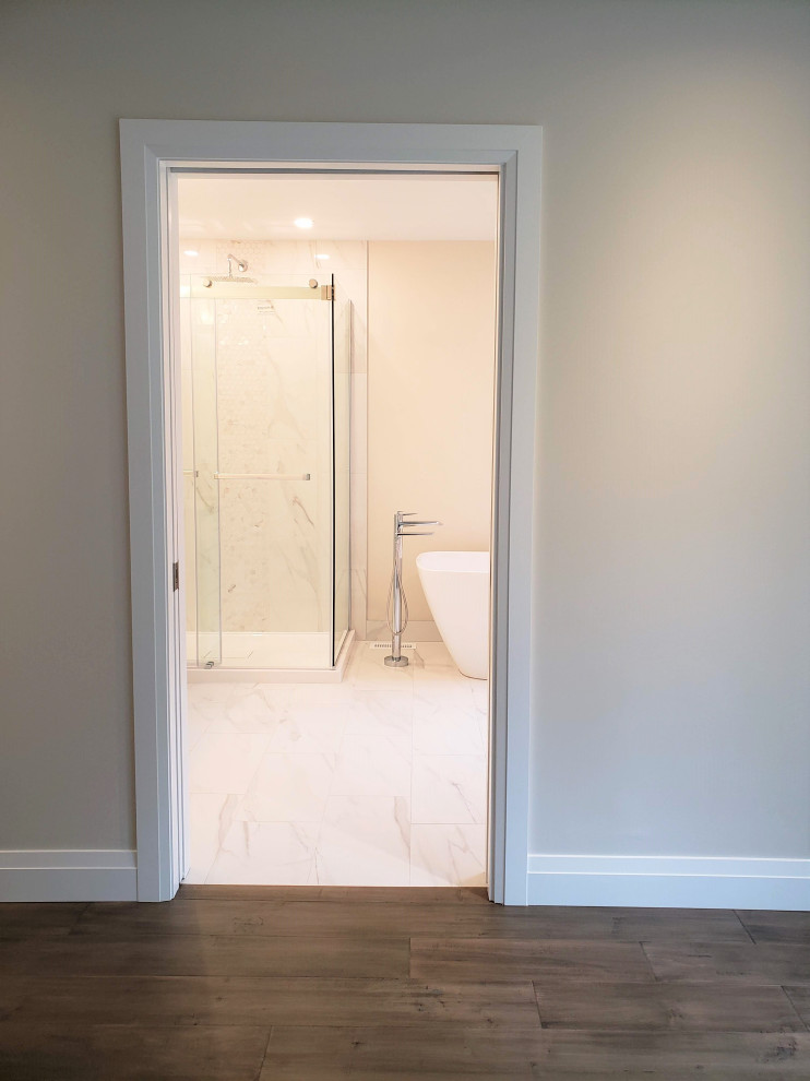 Cette image montre une grande salle de bain principale minimaliste avec une baignoire indépendante, une douche d'angle, un carrelage blanc, des carreaux de porcelaine, un sol en carrelage de porcelaine, un sol blanc, une cabine de douche à porte coulissante et meuble-lavabo encastré.