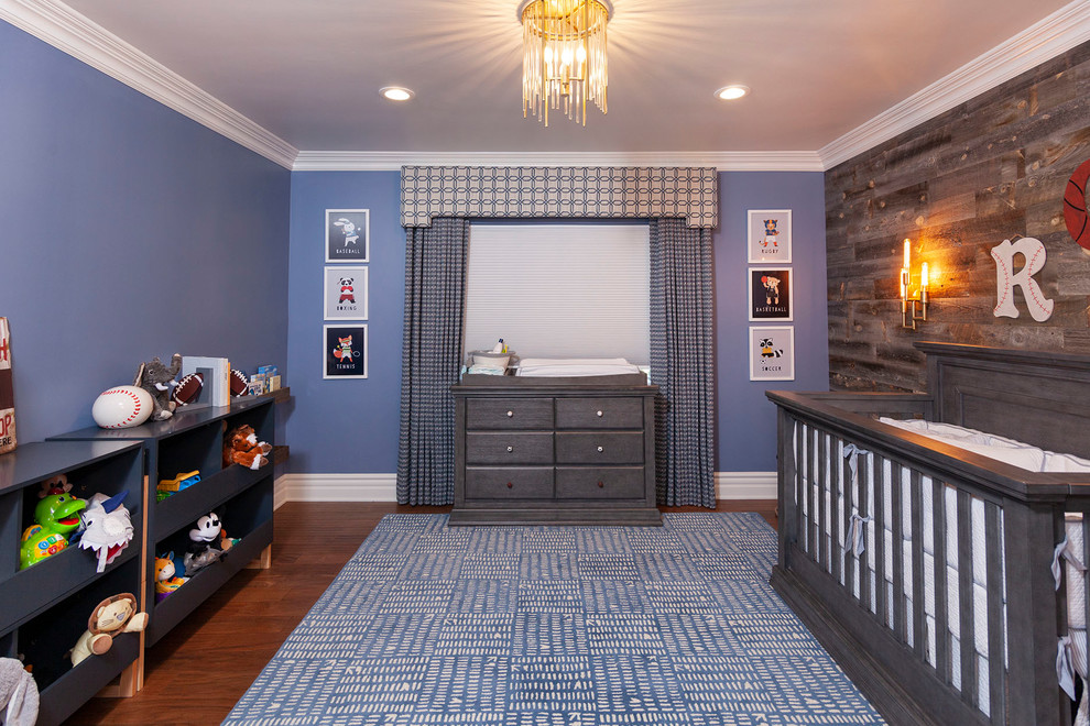 This is an example of a transitional nursery for boys in Los Angeles with blue walls, dark hardwood floors and brown floor.