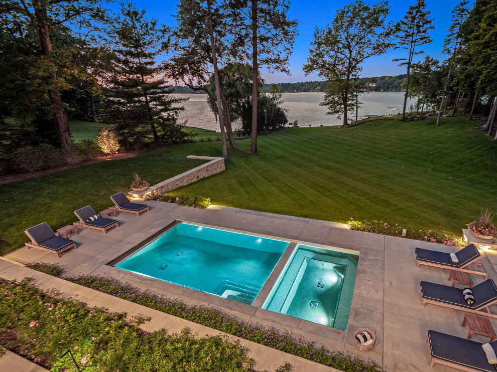 Réalisation d'un très grand piscine avec aménagement paysager arrière minimaliste rectangle avec une dalle de béton.