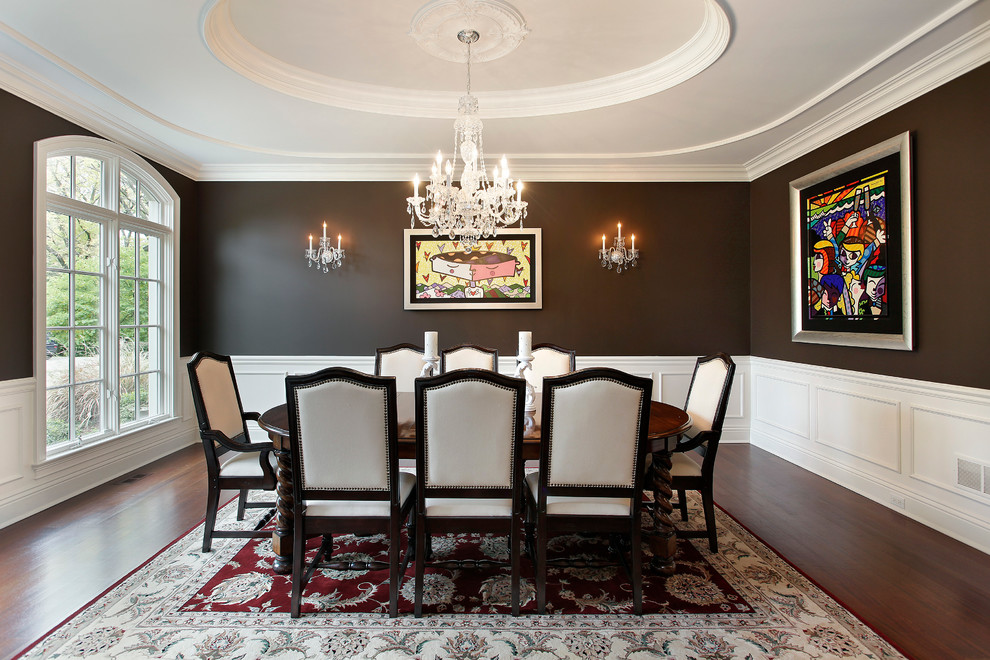 This is an example of a large traditional separate dining room in Chicago with black walls, dark hardwood floors, no fireplace and brown floor.