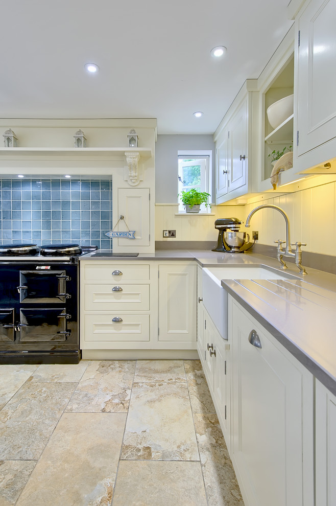 Inspiration for a large traditional u-shaped eat-in kitchen in Cambridgeshire with a farmhouse sink, recessed-panel cabinets, light wood cabinets, blue splashback, porcelain splashback, black appliances and terra-cotta floors.