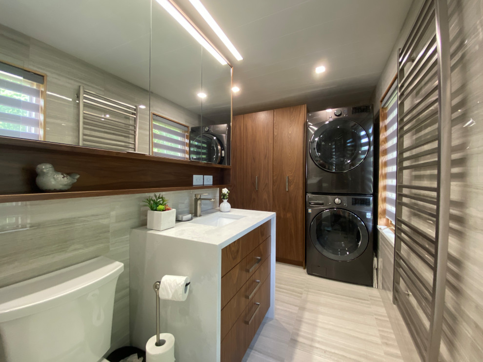 Design ideas for a small contemporary galley utility room in Other with a single-bowl sink, flat-panel cabinets, medium wood cabinets, quartz benchtops, grey splashback, porcelain splashback, grey walls, porcelain floors, a stacked washer and dryer, grey floor, white benchtop and timber.