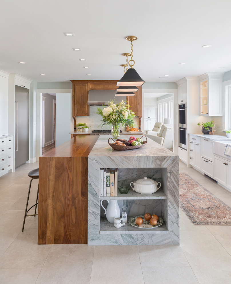 Inspiration for a large traditional kitchen/diner in Minneapolis with a belfast sink, recessed-panel cabinets, white cabinets, quartz worktops, ceramic splashback, stainless steel appliances, porcelain flooring, an island, beige floors and white worktops.